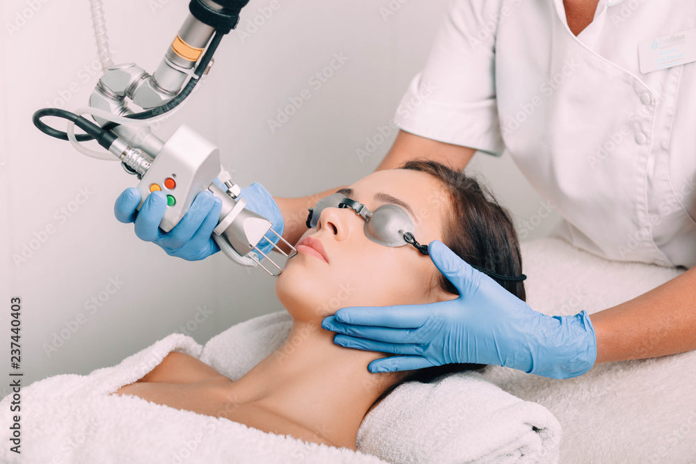 Woman receiving a laser facial treatment from a professional in a clinical setting.